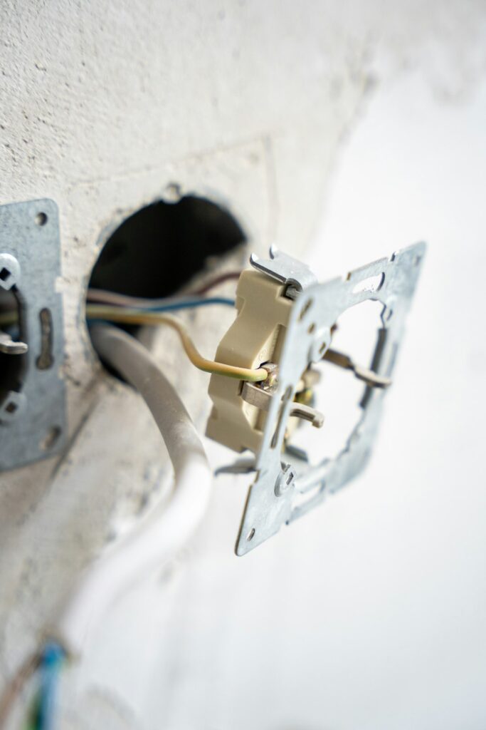 A person using a screwdriver to replace an electrical wall outlet in a residential setting.